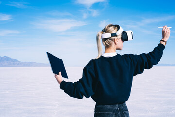 Female traveler exploring virtual reality with modern devices in salt pan