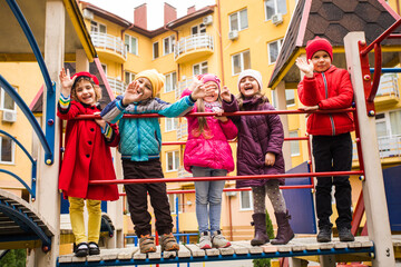 Obraz na płótnie Canvas the smiling kids are standing together on the playground equipment