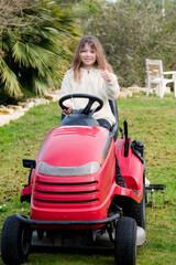 Fototapeta na wymiar pretty young girl passing self-propelled mower in the garden