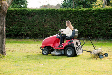 pretty young girl passing self-propelled mower in the garden