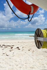 Obraz premium A lifebuoy and Lifeline at a Caribbean beach in Mexico, ocean and partly cloudy sky in the background. Travel and vacation concept.