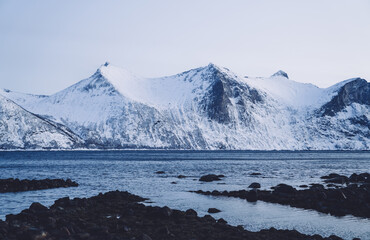 Tall hills and rocks over cold freezing water lake on northern landscape environment, frosty white wild location in arctic destination on winter season