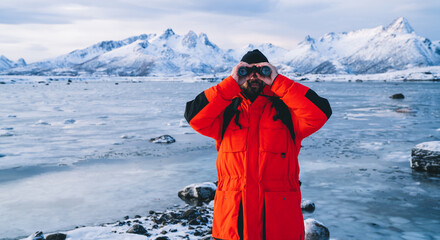 Fototapeta na wymiar Man with binocular looking at camera on frozen shore