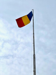 The National flag of Romania winding on a blue sky background
