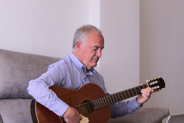 Mature man playing guitar alone at home. Concept music in confinement time, covid19.