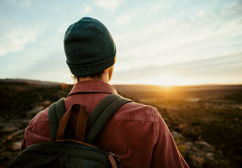 Caucasian male free spirit wearing beanie walking in wilderness watching sunset