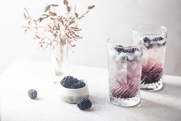 Refreshing Blackberry Lemonade with ice in crystal glasses on white background