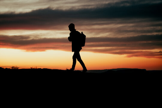 Silhouette male adventurer hiking during sunset on mountain top