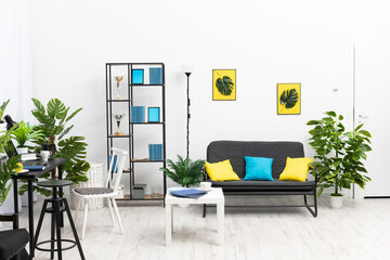 A large bright living room in the house with black furniture and accessories in blue and yellow. Modern interior design of the apartment.