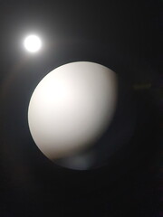 An abstract image of a light bulb that looks like an image of an obscured world and a luminous moon
