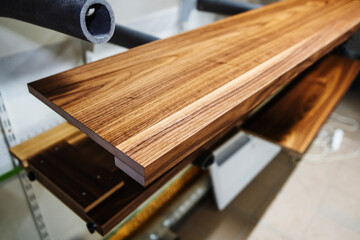 Furniture manufacturing. A fragment of a wooden, varnished part in a drying room for painted products. Close-up. Selective focus