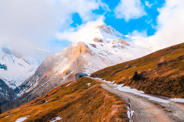landscape in the mountains with snow on the peaks and small road
