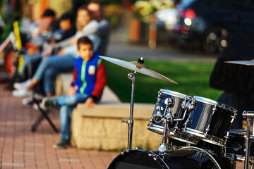 Street musicians. Drum set outdoors with spectators in the background. Unrecognizable faces....
