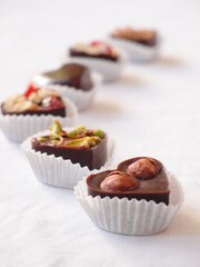 Delicious homemade chocolate with nuts and berries on a white tablecloth. chocolate candies close up
