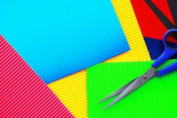 Sheets of colored paper, iridescent palette of colored paper, rainbow colors. Top view on table with colored paper and scissors.