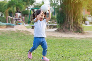 Happy Asian baby girl running or jumping and playing at the park or garden field. She smiling and laughing. Child aged 2-3 years old. Relaxation and exercise for health. Development of kid concept.