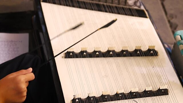 Close up of hands playing the Khim or dulcimer, a traditional Thai classical musical instrument