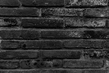 Texture of old dark scary dirty crumbling brick wall of ancient city. Uneven pitted surface of the brickwork of the damp basement with holes and worn. Decayed burnt brickwall background for 3D design