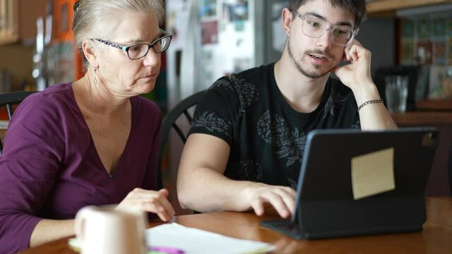 Closeup of home school education parent teaching son at home. Social distancing and self isolation in quarantine lockdown. A Young woman mother teaches her son and works with him on a laptop at home.