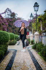 Fototapeta na wymiar girl walking with an umbrella. spring rainy days and walks. city of lisbon. travel and walks through beautiful places