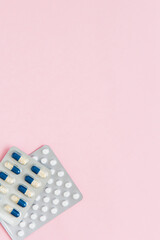 Packaging of white pills and capsules with medicine on pink background. Women Health. Disease prevention. Copy space.