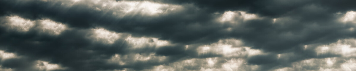 Fototapeta na wymiar panorama dramatic sun rays through a cloudy dark sky 