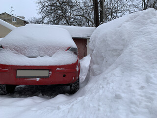 The car was covered with snow in the parking lot. Cars under a large layer of snow. Snowfall on the...