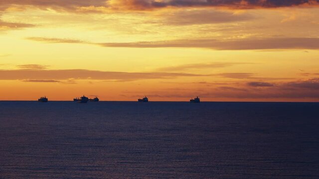 On the beam. Ocean-going vessels waiting to enter the port. Sunset sky and ship lights
