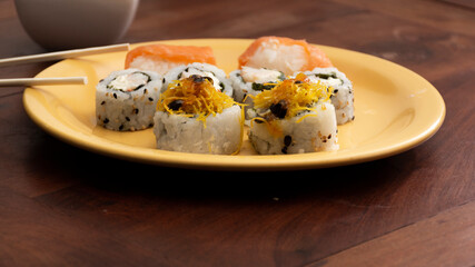 Sushi on a yellow plate on a wooden table. Maki. Sashimi. Salmon, Asian, Japanese.