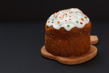 Easter cake and wooden cutting board in black background.