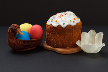 Easter cake and colorful Easter eggs in wicker basket.