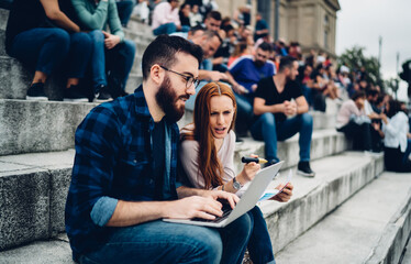 Male and puzzled female freelancers discussing web project during remote working on laptop technology, Caucasian digital nomad browsing wireless publication while collaborating on banking application