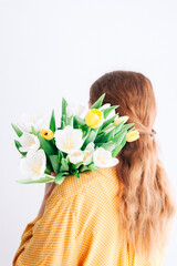 Naklejka premium Back view of redhead woman with Yellow and white tulip bouquet on her shoulder.
