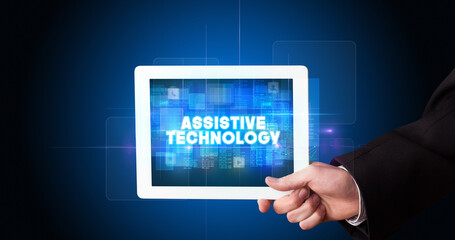 Young business person working on tablet and shows the inscription: ASSISTIVE TECHNOLOGY