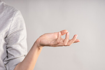 Naklejka premium Elegant female hand, pointing to the side. palm holds something, a blank for the design. businesswoman in a casual gray shirt makes a hand gesture