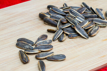 Roasted sunflower seeds on a wooden board with red cloth