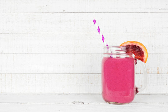 Red Blood Orange Smoothie In A Mason Jar Glass. Side View On A White Wood Background.