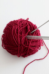 ball of red wool yarn and five knitting needles