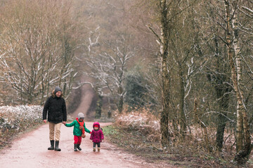Fototapeta na wymiar Happy father with children walking in the winter forest. Dad, son, daughter. Warmly dressed.