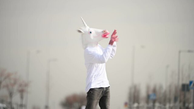 Man with unicorn mask making funny gestures
