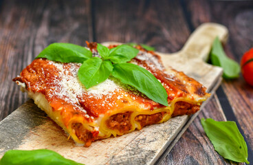 Cannelloni bolognese and parmesan cheese  on a wooden rustic  background.Home made italian meal
