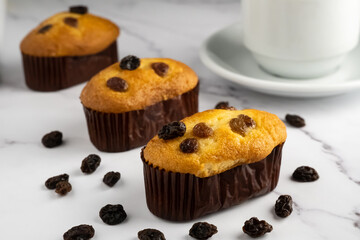 raisin muffins and blurred white tea cup on white marble table top