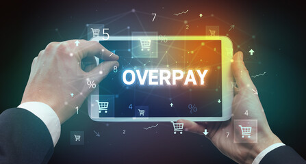 Close-up of a hand holding tablet with OVERPAY inscription, online shopping concept