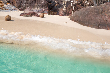 A seething sea wave rolls along the coast with white sand to the rocky coast. Sea recreation and tourism