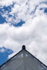 Top of the greenhouse roof made of glass on the cloudy sunny blue sky background
