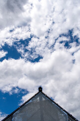 Top of the greenhouse roof made of glass on the cloudy sunny blue sky background
