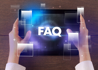 Close-up of a hand holding tablet with FAQ abbreviation, modern technology concept