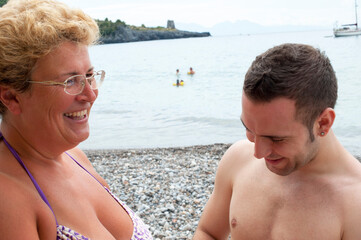A blond mother with her shorthaired son having fun at the beach.