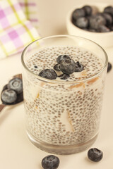 Fototapeta na wymiar Healthy breakfast on a sunny morning. Chia seed pudding with blueberries and pieces of mango on grey background.