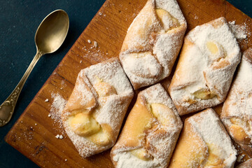 Sweet cakes with curd sprinkled with powdered sugar on a wooden board, top view
